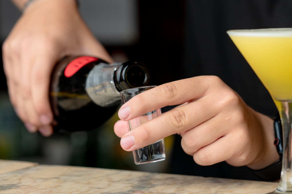 Bártender tölt egy shot pohárba italozás előtt