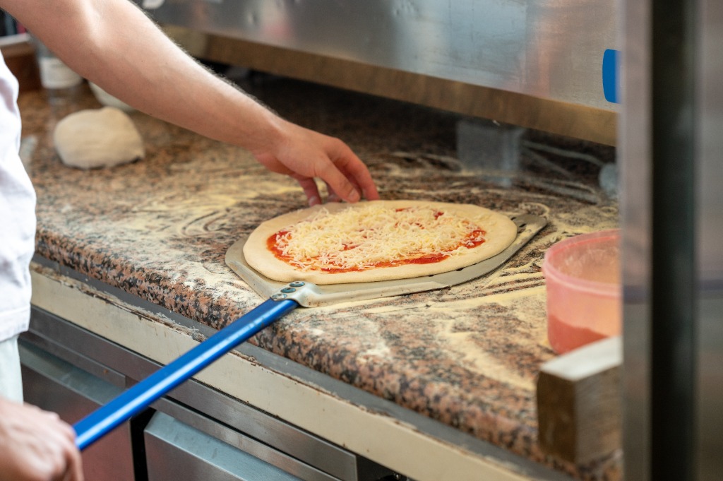 Nyers pizza tejfölös alappal, baconnel és lilahagymával a lapáton
