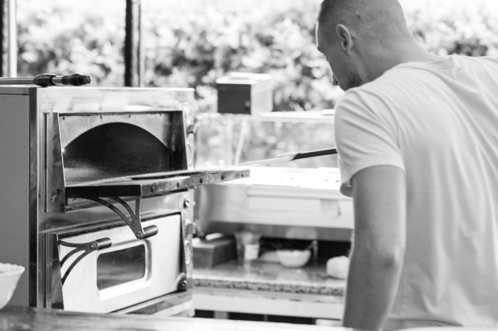 Pizzakészítő ellenőrzi a forró samottlapos pizzakemencét