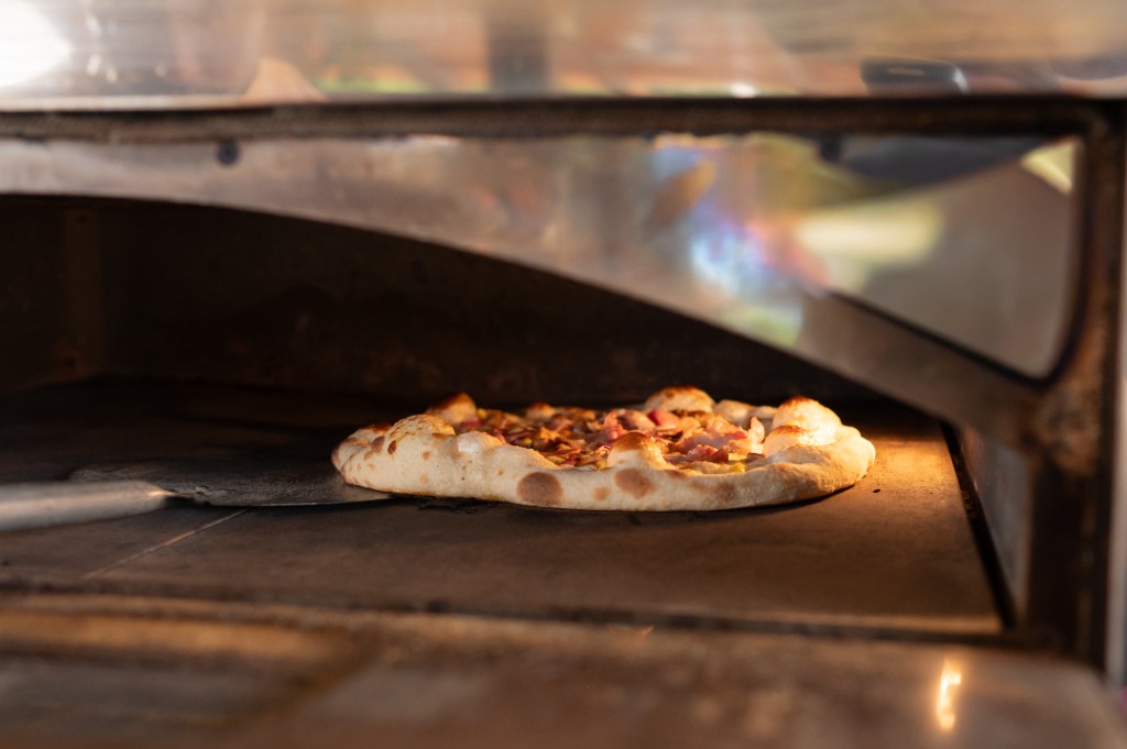 Pizza sül a forró samottlapos pizzakemencében
