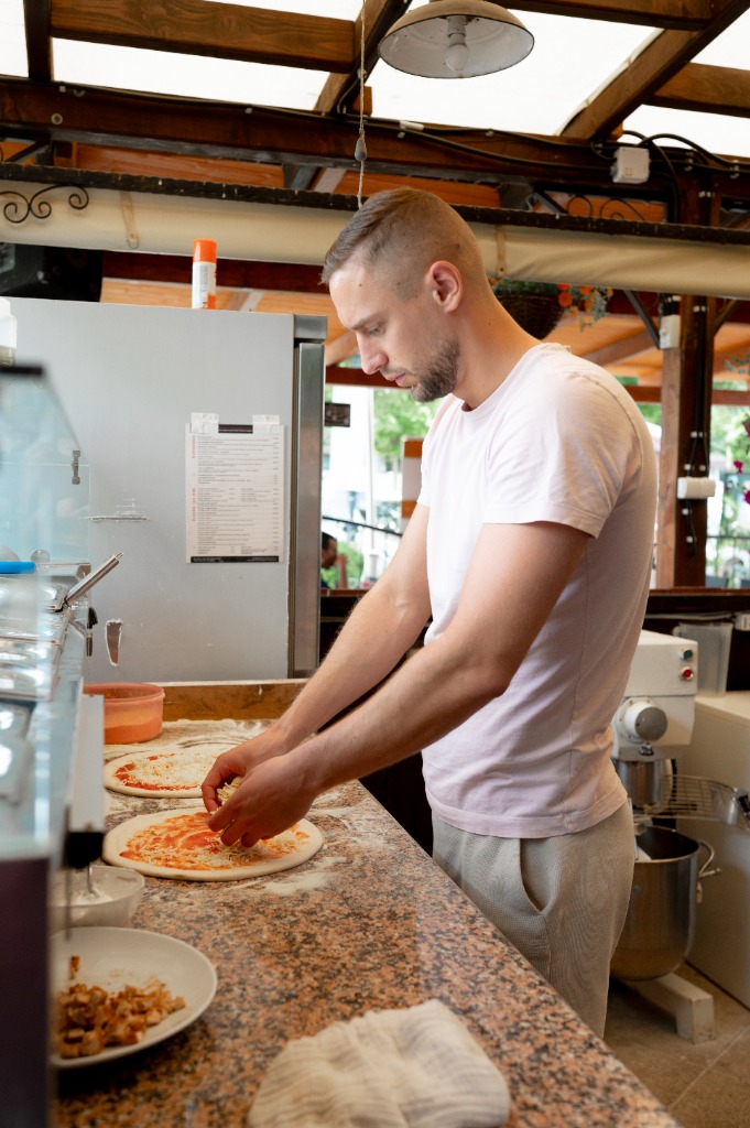 Pizzakészítő fém lapáttal emeli meg a pizzát a pulton