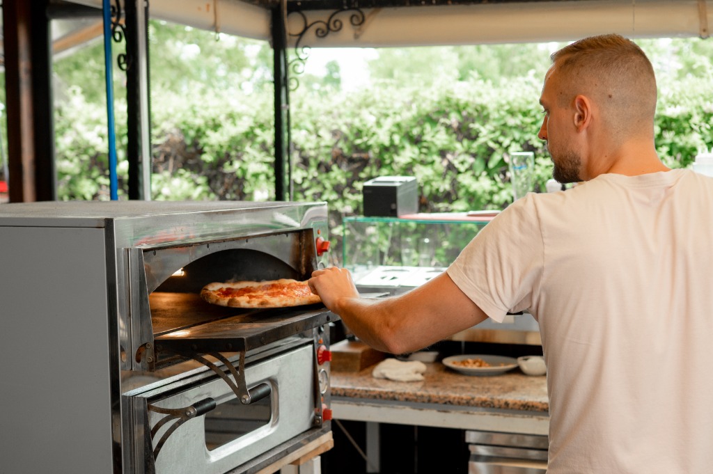 A sülő pizza közeli képe a megvilágított kemencében