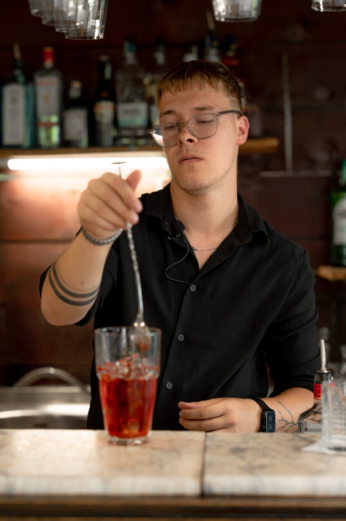 Bártender figyeli az ital keveredését a pohárban