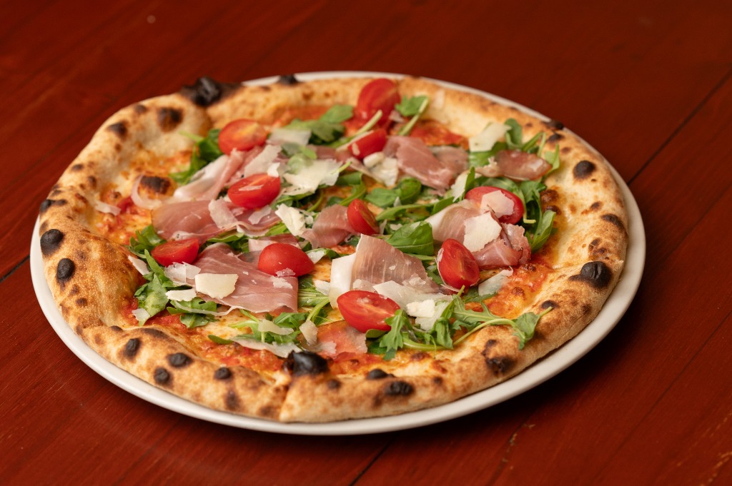 Kemencés Prosciutto pizza friss rucolával, paradicsommal és parmezán forgáccsal